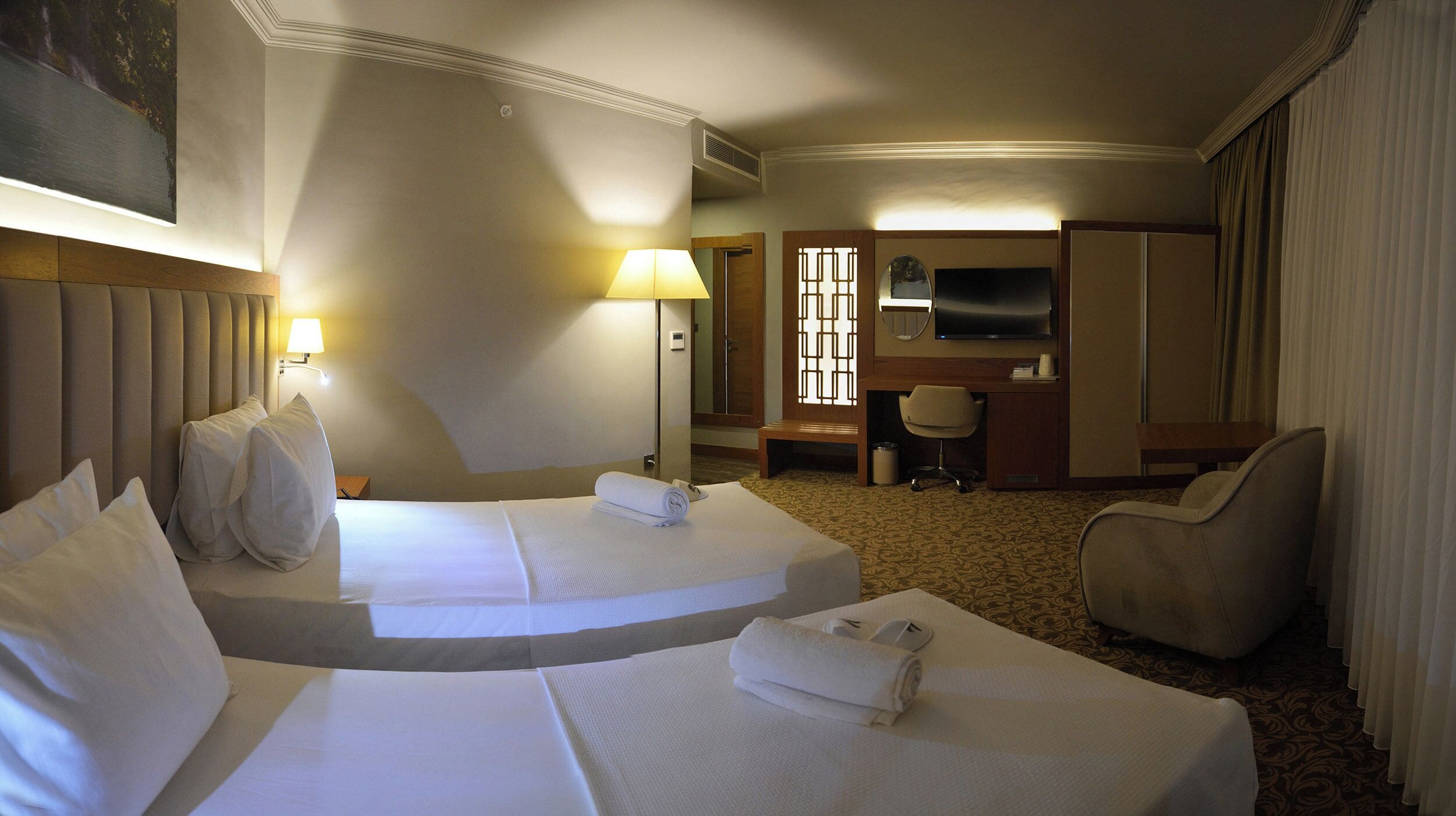 Een hotelkamer met twee bedden, een bureau, een stoel, een televisie en een badkamer.