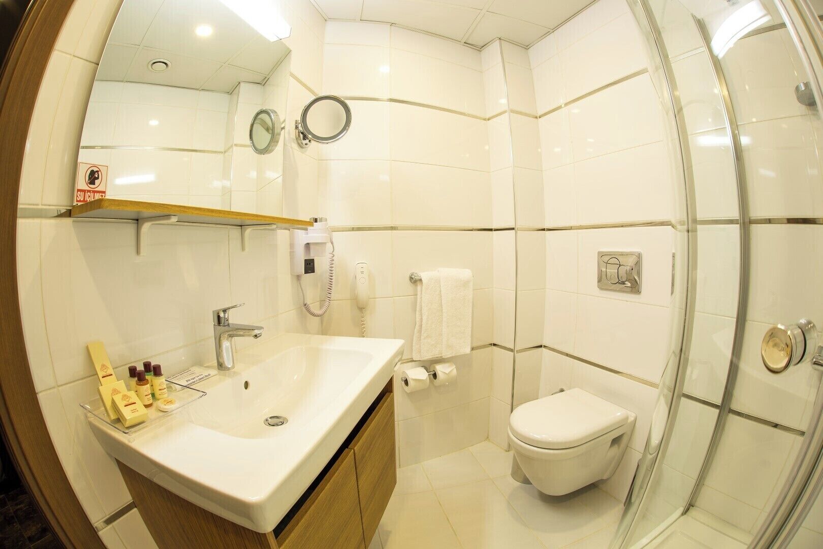 Et moderne badeværelse med vask, spejl, toilet og brusebad.