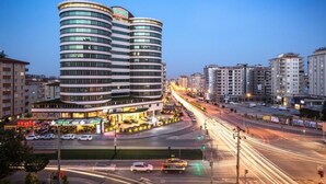 A modern hotel with a curved facade, multiple floors, and a ground-level commercial area with visible signage.