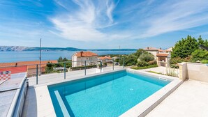 Una piscina con vistas despejadas al mar y edificios circundantes.
