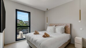 A modern bedroom with a large bed, a sliding glass door to the outside, and a small bedside table. - Luxury appartement avec parking (Saint-Tropez)