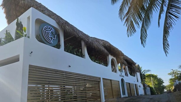 A building with a thatched roof, a large logo, and a gated entrance.