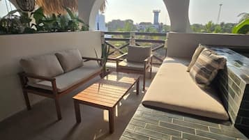 Un espacio de estar al aire libre con techo de paja, un sofá, una mesa y sillas.