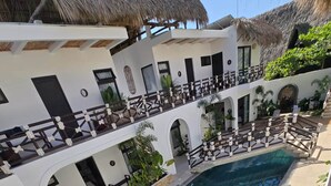 A pool area with a clear view of the pool, lounge chairs, and a thatched roof structure.