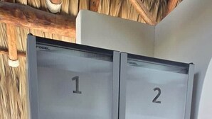 A set of double doors with numbered panels, likely indicating room numbers, in a room with a tiled floor and a visible trash bin.