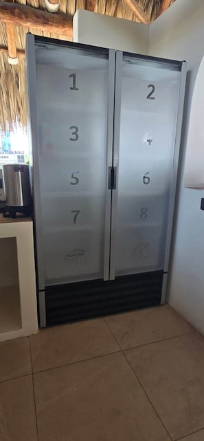 A set of double doors with numbered panels, likely indicating room numbers, in a room with a tiled floor and a visible trash bin. - To complete (El Paredon)