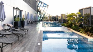 A modern outdoor pool area with lounge chairs and a glass-enclosed seating area.