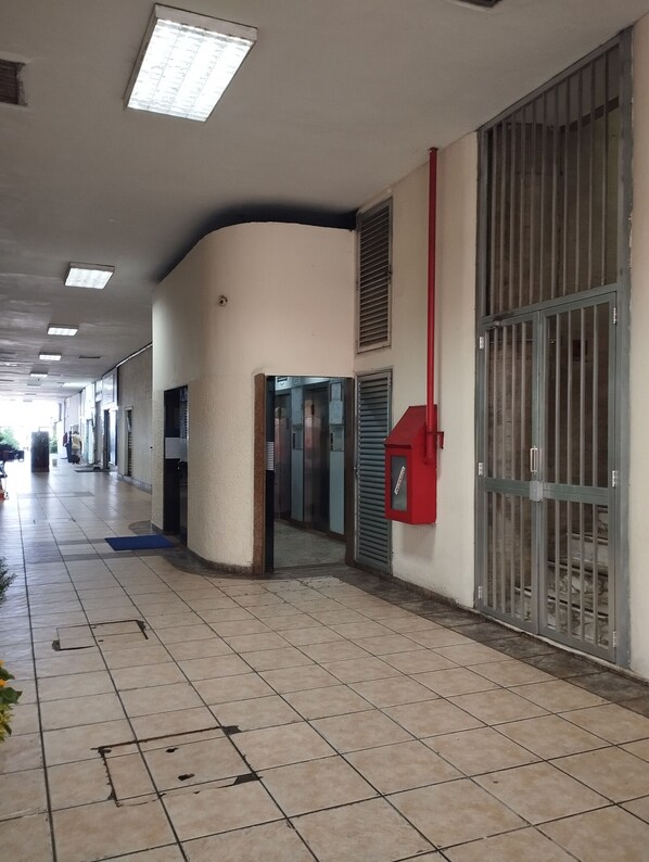 A corridor with tiled flooring, a red mailbox, and barred windows.