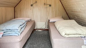 A small, enclosed sleeping area with two bunk beds, wooden walls, and a simple electrical outlet.