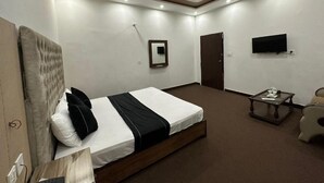 Ein modernes Hotelzimmer mit einem großen Bett, einem flachbildfernseher an der Wand und einem kleinen Tisch mit einem Stuhl.