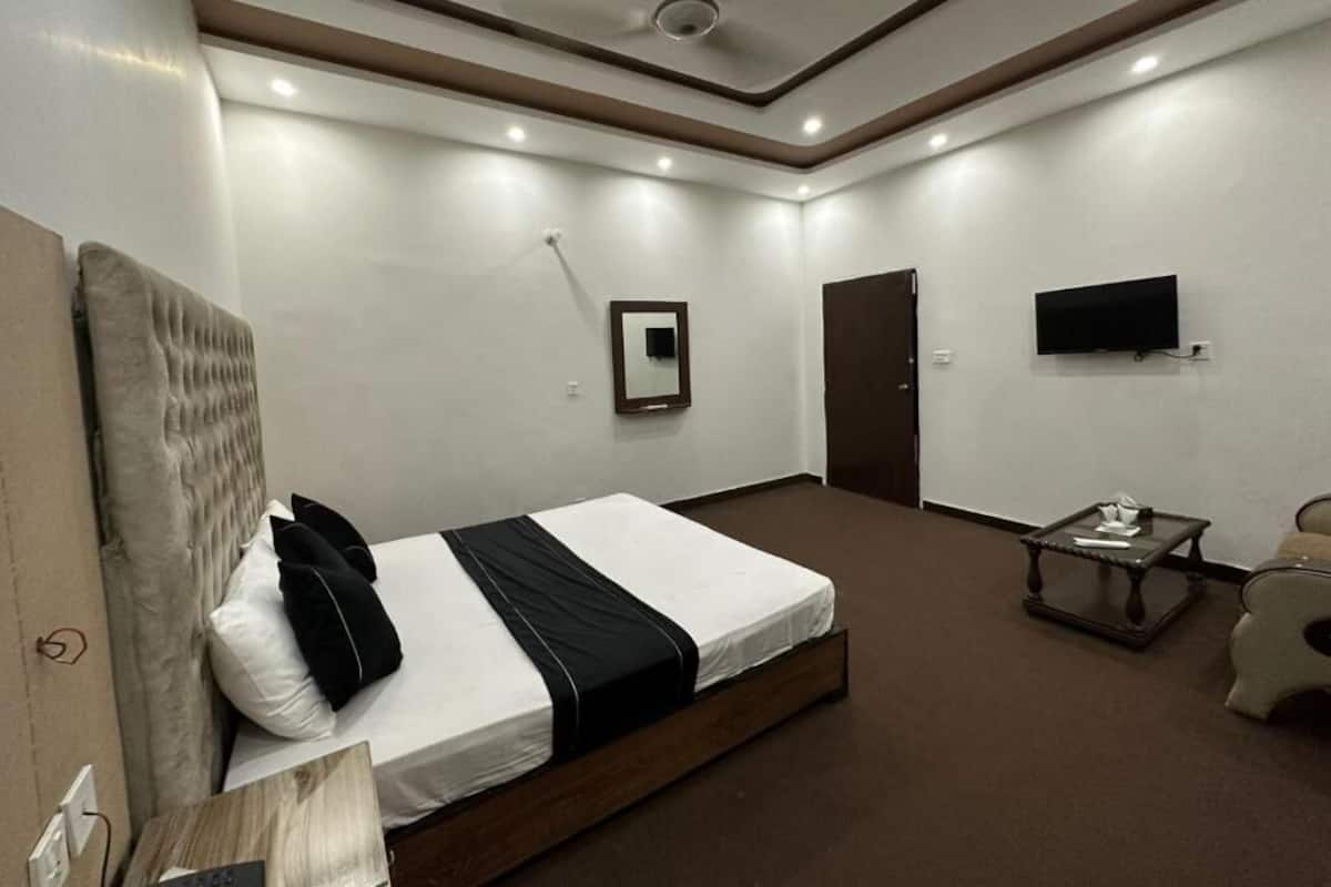 Una habitación de hotel moderna con una cama grande, un televisor de pantalla plana en la pared y una pequeña mesa con una silla.