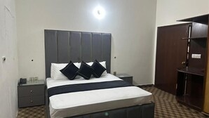 Ein Schlafzimmer mit einem großen Bett, einem Nachttisch, einem Kleiderschrank und Teppichboden.