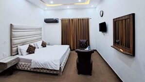 Ein modernes Hotelzimmer mit Bett, Deckenventilator, Flachbildfernseher und einem Fenster mit Vorhängen.