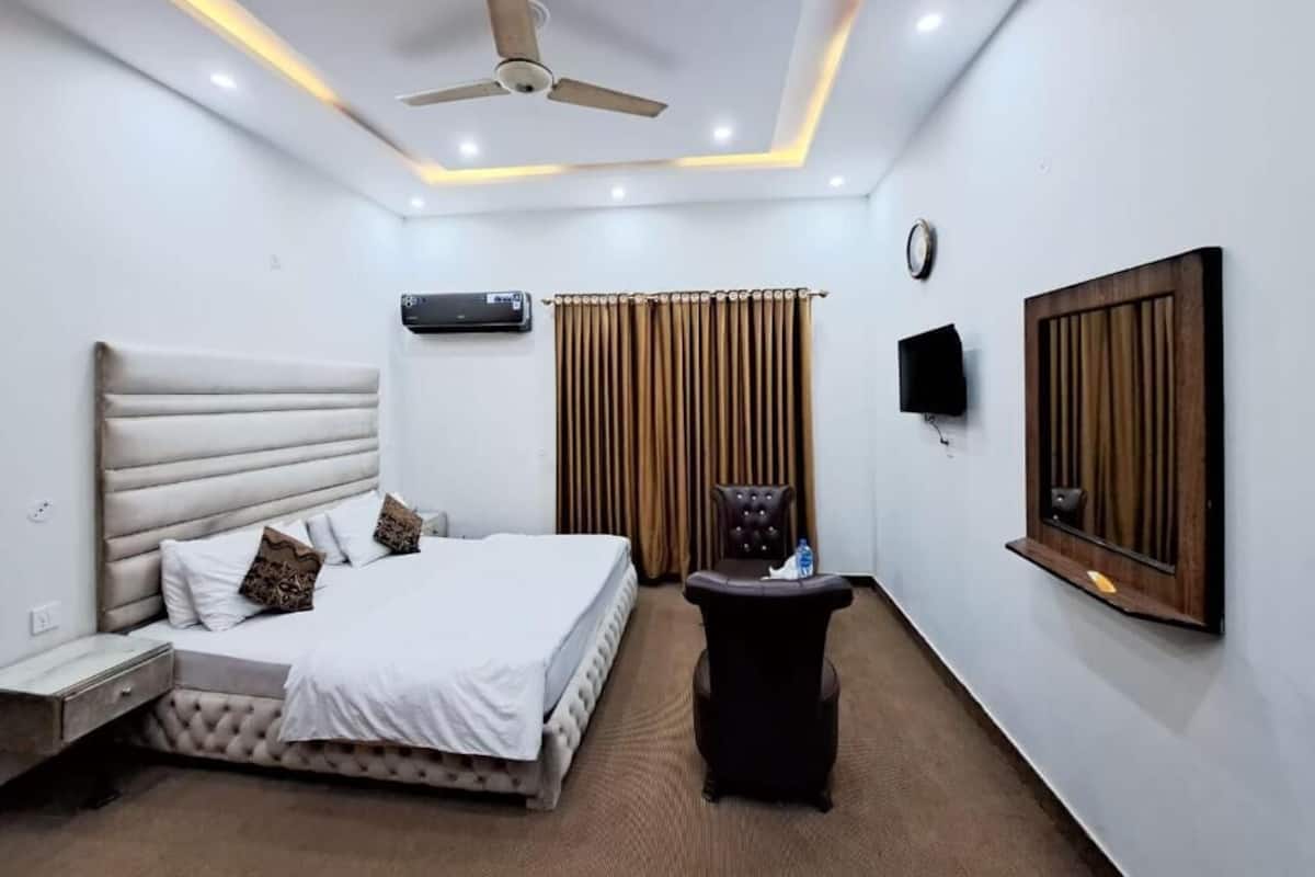 Una habitación de hotel moderna con una cama, ventilador de techo, televisor de pantalla plana y ventana con cortinas.