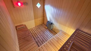 A sauna room with wooden benches, a heater, and a small window. - Lovely home in Grenaa with sauna (Grenaa)