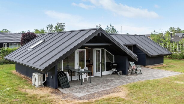 A modern house with a sloped roof, a covered patio, and a grill area. - Lovely home in Grenaa with sauna (Grenaa)