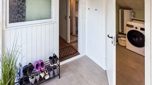 A laundry room with a washing machine, a drying rack, and a shoe rack with various shoes. - Lovely home in Grenaa with sauna (Grenaa)