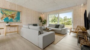 Un salon moderne avec une grande fenêtre, une carte accrochée au mur et un plancher en bois.