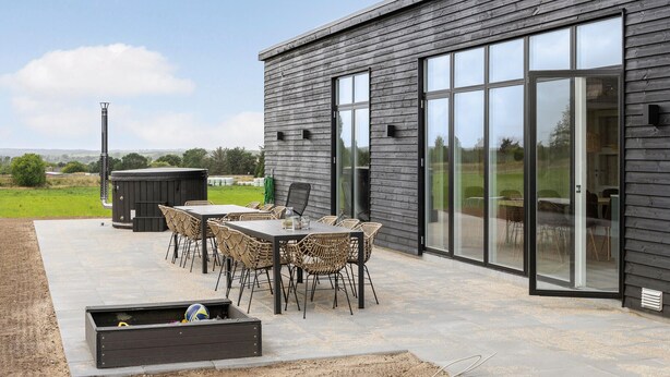 Une terrasse extérieure avec une table et des chaises, un jacuzzi et une grande porte-fenêtre coulissante.