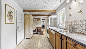 A kitchen with wooden beams, a tiled backsplash, and a dining area with a table and chairs. - 5 bedroom cozy home in ørsted (Ørsted)