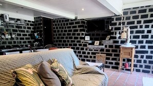 A cozy living room with a sofa, a brick wall, and a television.