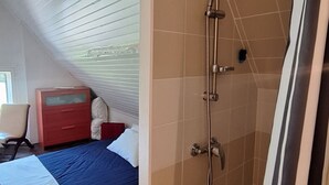 A bedroom with a bed, a dresser, and a shower.