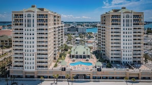 A hotel with a central pool, multiple balconies, and a view of the surrounding cityscape.