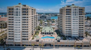A hotel with a central pool, multiple balconies, and a view of the surrounding cityscape.