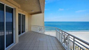 A balcony with a view of the beach and ocean.