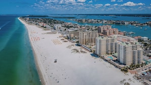 A coastal cityscape with a wide beach, high-rise hotels, and a marina.