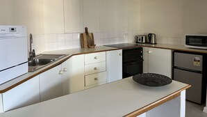 A modern kitchen with white cabinets, a stainless steel sink, a microwave, a toaster, and a small refrigerator.