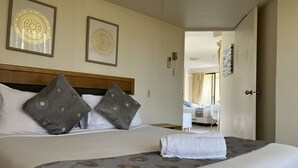 A neatly made bed with a patterned bedspread, two pillows with a circular design, and a framed artwork on the wall.