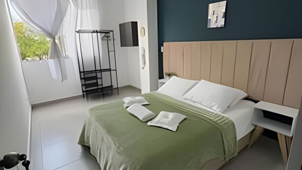 Une chambre à coucher moderne avec un lit, une tête de lit, une fenêtre avec des rideaux et un téléviseur fixé au mur.