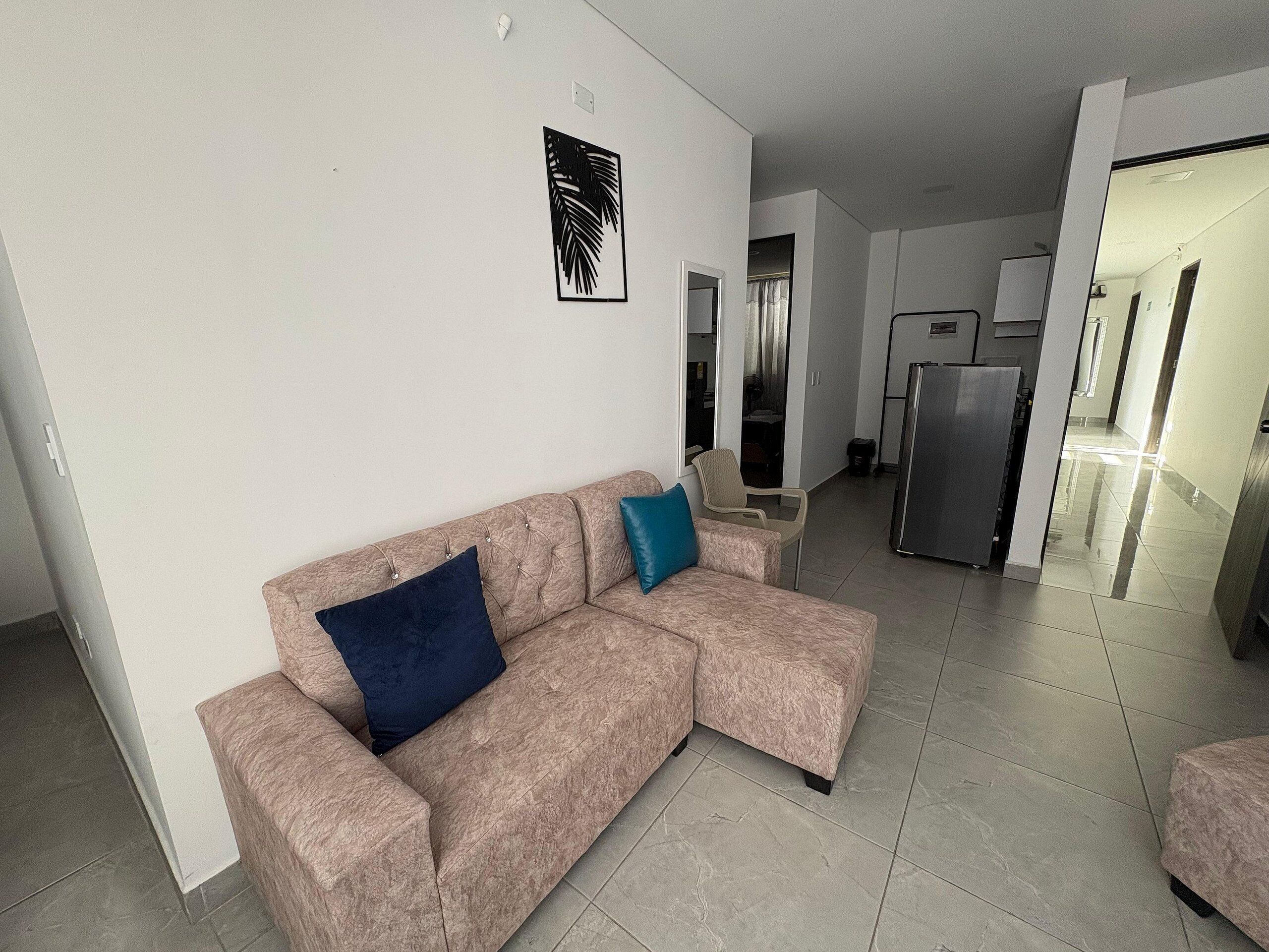 Een woonkamer met een bank, een tafeltje en een koelkast.
