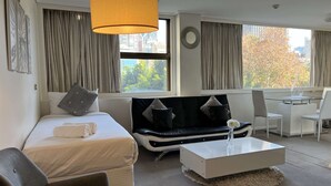 Una camera d'albergo moderna con un letto, un divano, un tavolino da caffè e una scrivania.