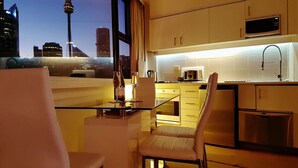 Una cucina moderna con vista sulla città, che include un'area pranzo con sedie e tavolo, e un forno a microonde sopra il bancone.