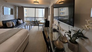 A hotel room with a bed, a sofa, a dining table, and a large mirror.