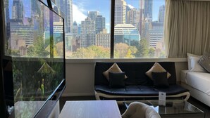 A modern living room with a city view, a sofa, a chair, and a glass coffee table.