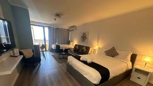A hotel room with a large bed, a desk, a chair, a TV, and a balcony. - Large City Studio with Big Balcony (Darlinghurst)