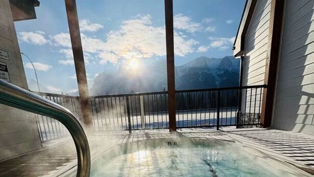 A clear pool with a view of mountains and a cloudy sky.