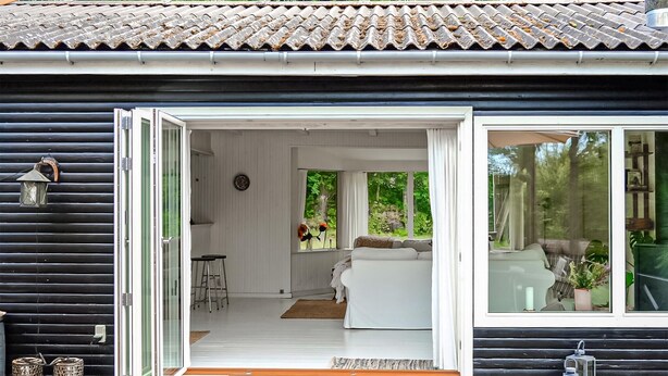A modern cabin with a sliding glass door leading to a living area with a sofa and a dining table.