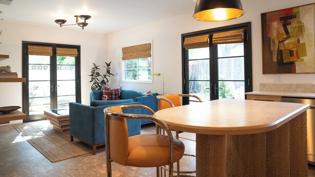 A modern kitchen with a central island, a dining area with a round table, and a living space with a blue sofa and orange chairs. - Spanish-style garden bungalow! (Burbank)