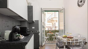 Una cocina moderna con encimera de mármol negro, estufa y zona de comedor con mesa y sillas.