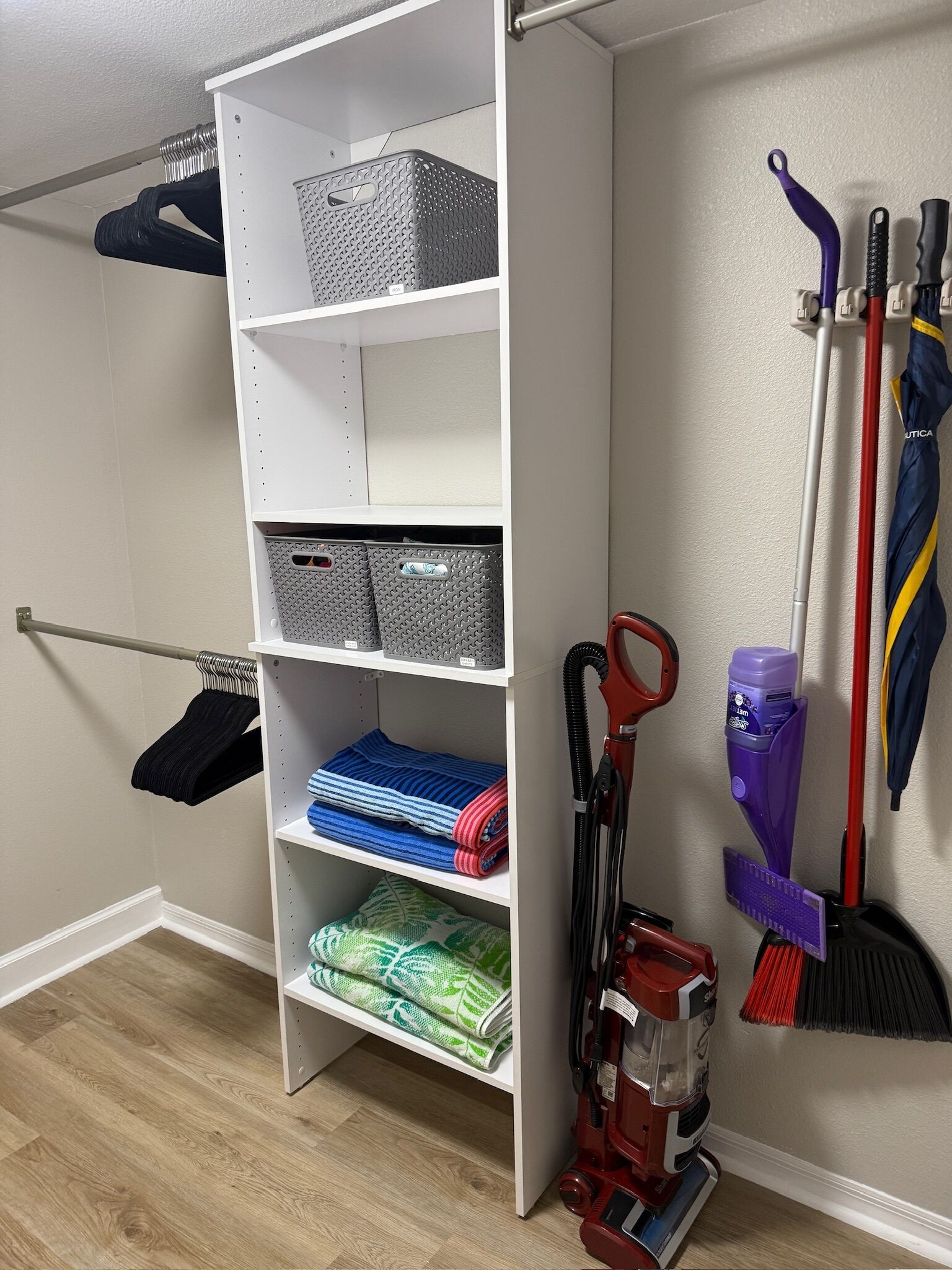 A storage unit with shelves holding baskets and folded towels.