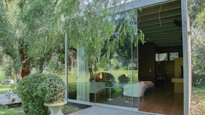 A modern house with a glass door leading to a living area with a sofa and a dining table. - Casa Cieneguilla by Wynwood House (Pachacamac)
