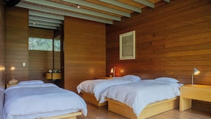 A room with two wooden beds, a nightstand with a lamp, and a wall-mounted light fixture. - Casa Cieneguilla by Wynwood House (Pachacamac)