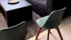 Un salón moderno con un sofá gris oscuro, una pequeña mesa de centro y una silla azul claro. Un cuadro grande de la cabeza de un toro está en la pared.