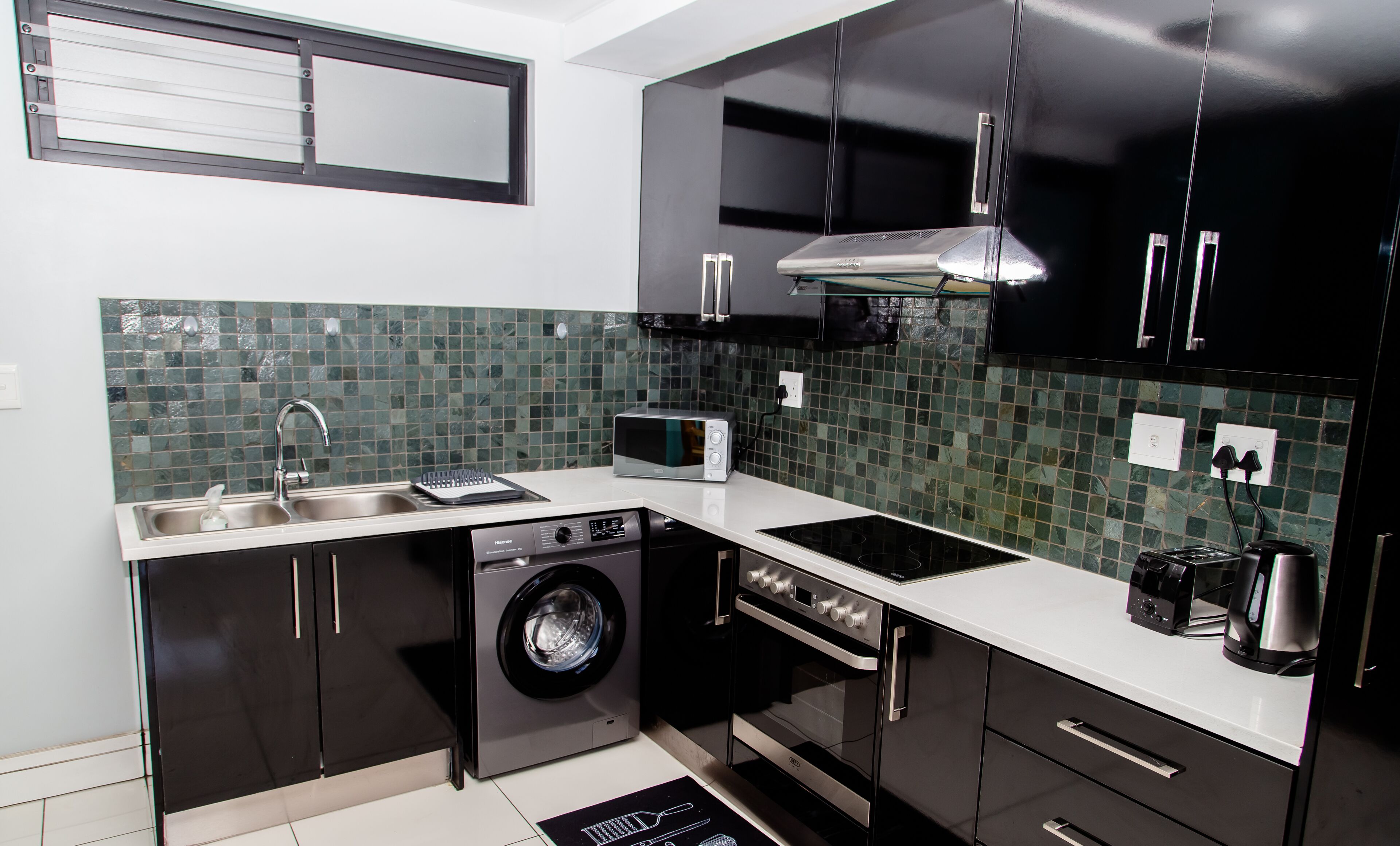 A modern kitchen with black cabinets, a stainless steel sink, a microwave, a dishwasher, and a stove.