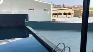Un área de piscina en la azotea con vistas despejadas a edificios en el fondo.
