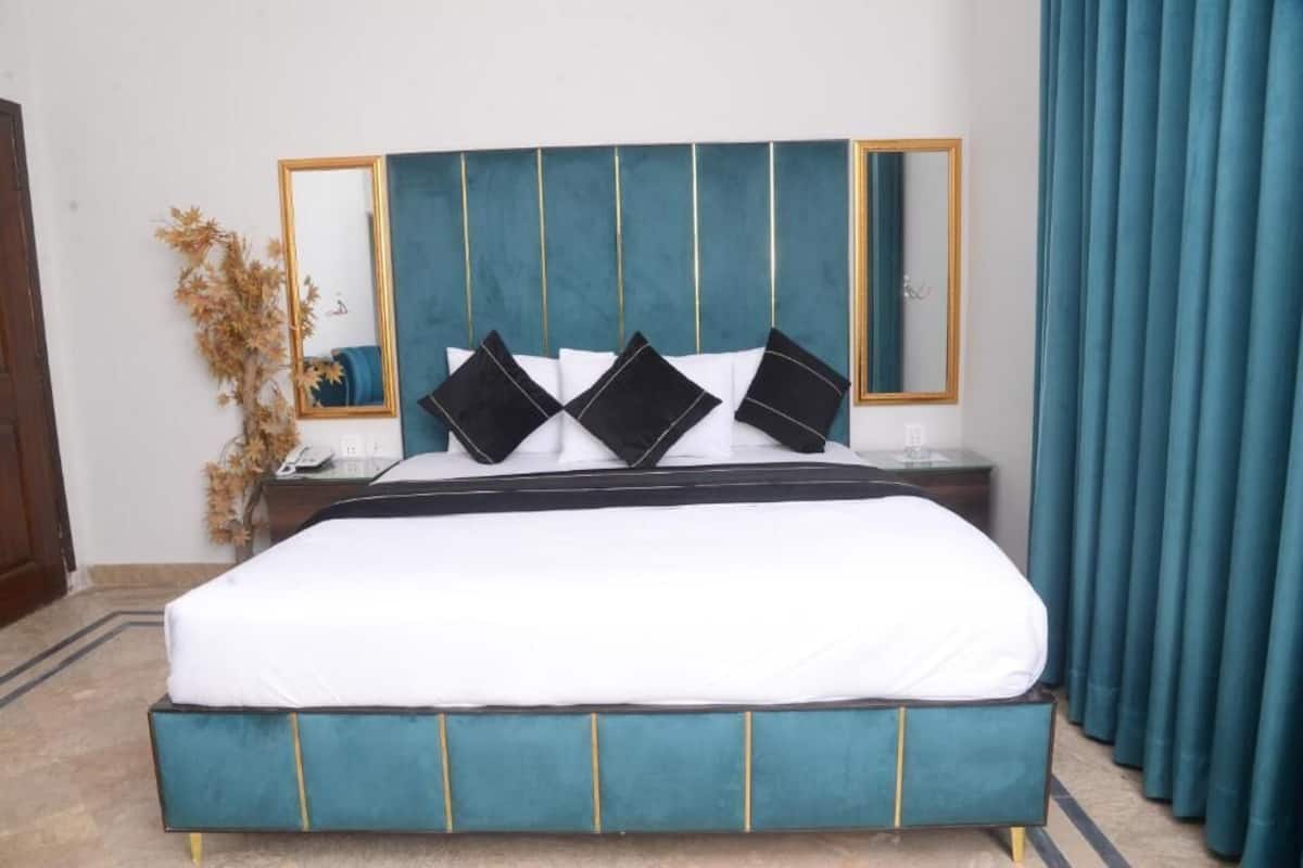 A bed with a teal upholstered headboard, white bedding, and black accent pillows.